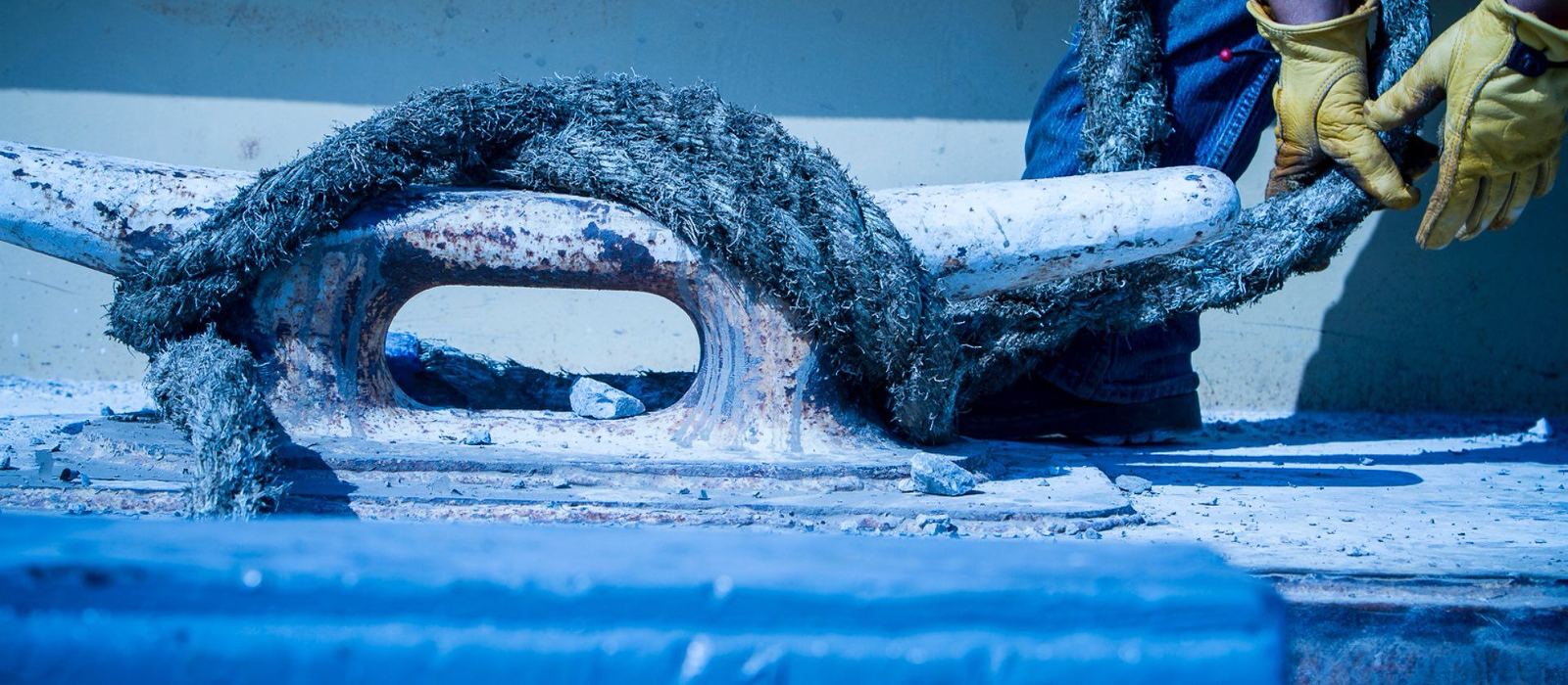 A deckhand in work gloves securing a mooring line on a barge cleat.